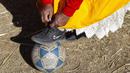 Seorang perempuan suku Aymara mengikat tali sepatu sebelum bermain sepak bola di distrik Juli, kota Puno, Peru selatan. (AFP/Carlos Mamani)