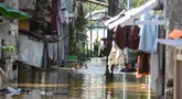 Warga beraktifitas saat banjir merendam pemukiman di Jalan Pirus, Kelurahan Bidara Cina, Jatinegara, Jakarta Timur, Minggu (6/7/2025). (merdeka.com/Arie Basuki)