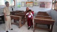 Ahmad Fattan Ali Akbar (10) digendong orangtuanya usai menerima pelajaran di ruangan kelas. (Liputan6.com/ Dian Kurniawan)
