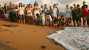 Warga menyaksikan saat anggota The Orange House Project melepaskan bayi penyu atau tukik di pantai El Mansouri, Tyre, Lebanon, Minggu (29/7). Keluarga dan anak-anak sekolah selalu diundang untuk menyaksikan pelepasliaran tukik. (Mahmoud ZAYYAT/AFP)