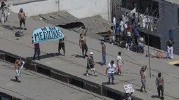 Narapidana membawa poster yang bertuliskan "Tidak ada obat-obatan" saat menggelar protes di Penjara Lurigancho, Lima, Peru, Selasa (28/4/2020). Narapidana mengeluhkan pihak berwenang tidak berbuat cukup untuk mencegah penyebaran COVID-19 dalam penjara. (AP Photo/Rodrigo Abd)