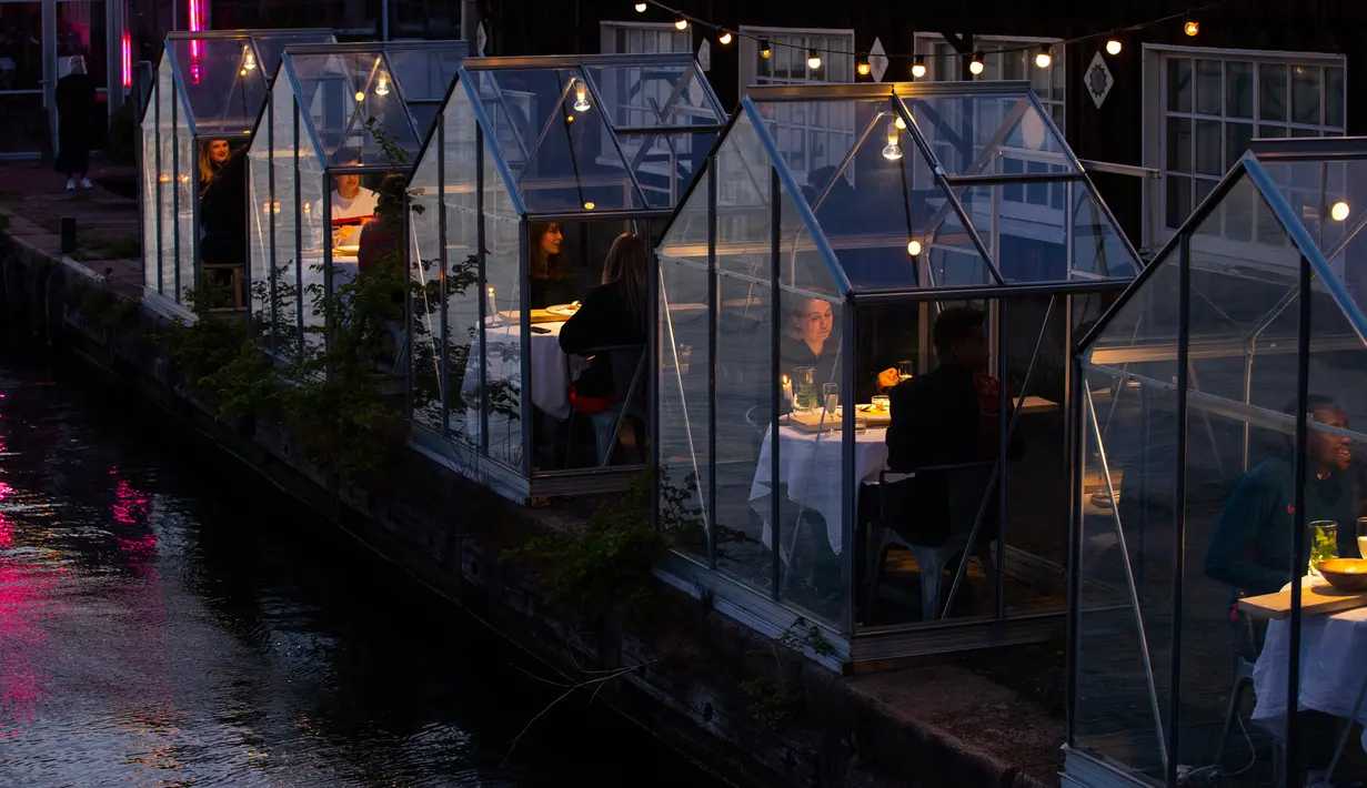 Pengunjung menikmati makanan mereka dalam kabin kaca berkonsep "quarantine greenhouses" selama uji coba, ketika Belanda berjuang melawan penyebaran COVID-19, di restoran Mediamatic, Amsterdam pada 5 Mei 2020. (AP/Peter Dejong)