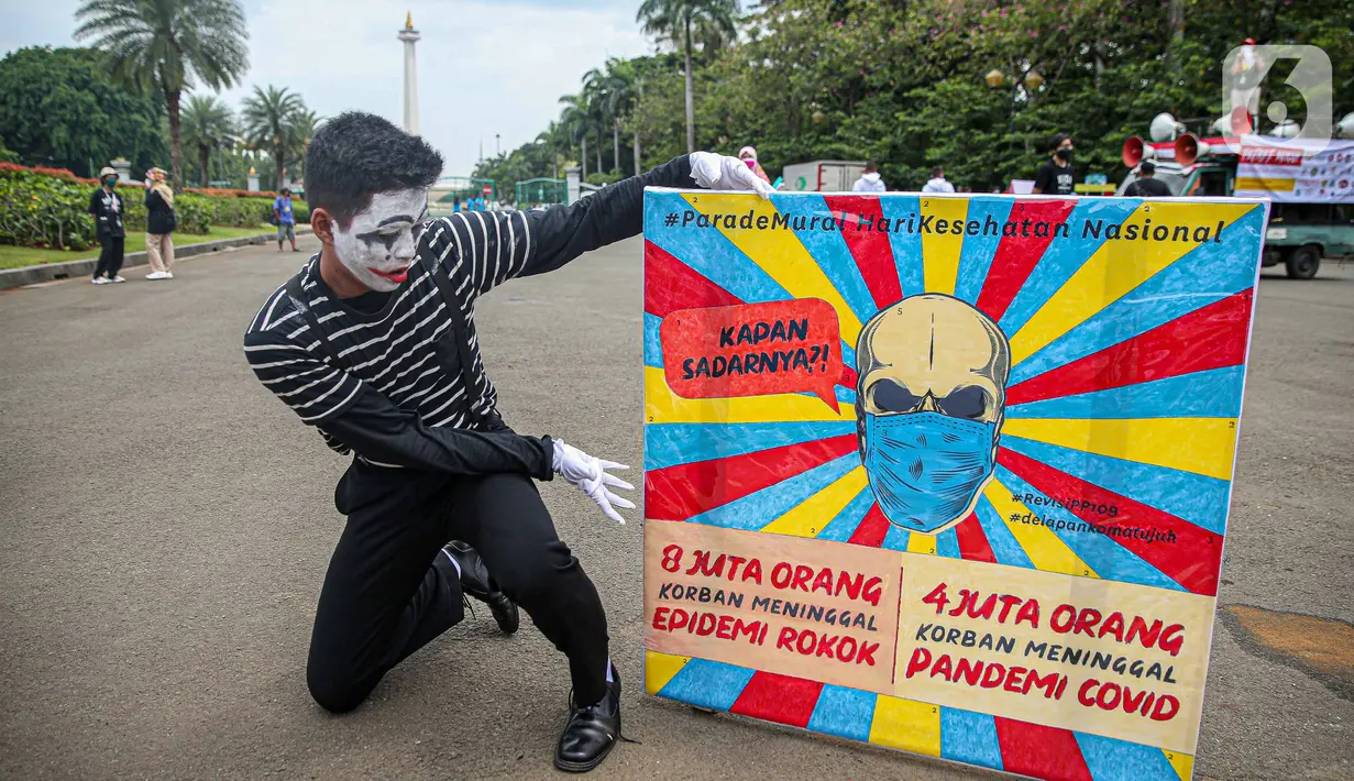 Seorang yang tergabung dalam Koalisi Masyarakat Peduli Kesehatan (KOMPAK) menunjukkan poster saat menggelar aksi #ParadeMural di kawasan Patung Arjuna Wijaya, Jakarta, Rabu (17/11/2021). Aksi tersebut untuk mendesak Presiden untuk mengesahkan Revisi PP 109/2012. (Liputan6.com/Faizal Fanani)