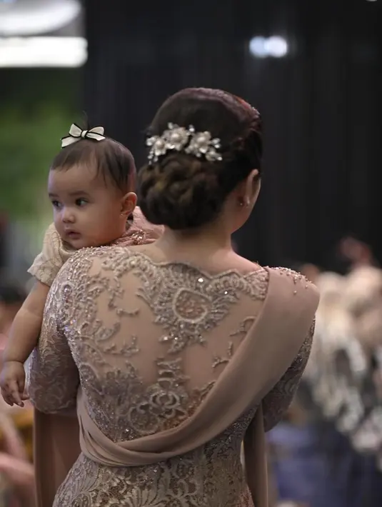 Di momen ini, Ashanty terlihat menggendong Azura, anak kedua Aurel yang juga didandani dengan outfit serasi. Terlihat gemas, Azura dengan pita mini di atas kepalanya terlihat anteng dipangkuan Ashanty. [Foto: Instagram/ashanty_ash]