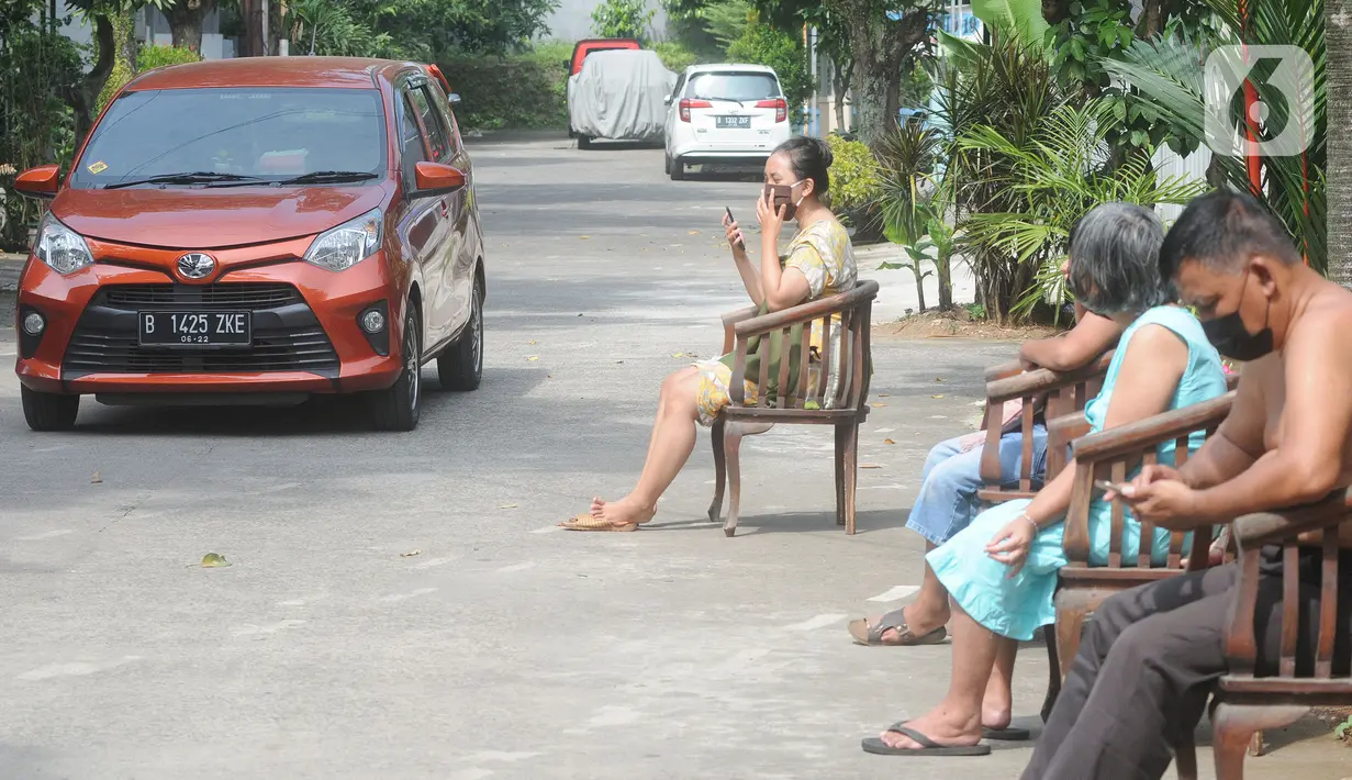 Pengendara melintasi warga yang sedang berjemur di pinggir jalan kompleks Perumahan Vila Cinere Mas, Depok, Kamis (8/7/2021). Saat ini lebih dari 50 warga Vila Cinere Mas terpapar Covid-19 dan menjalani isolasi mandiri di rumah masing-masing. (merdeka.com/Arie Basuki)