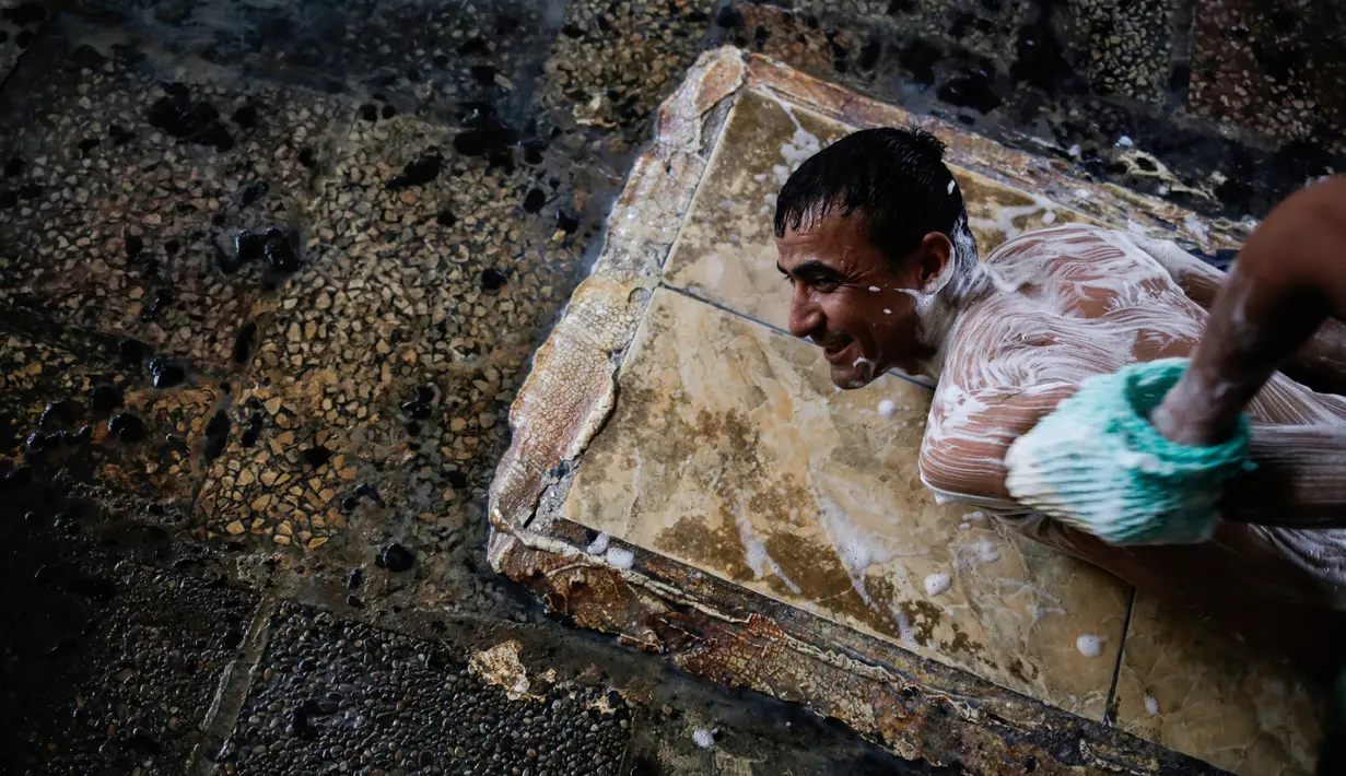 Pengunjung saat dipijat menggunakan scrub di kolam renang air hangat dari belerang di Hamam Alli, Mosul, Irak, (27/4). (AP Photo/Bram Janssen)