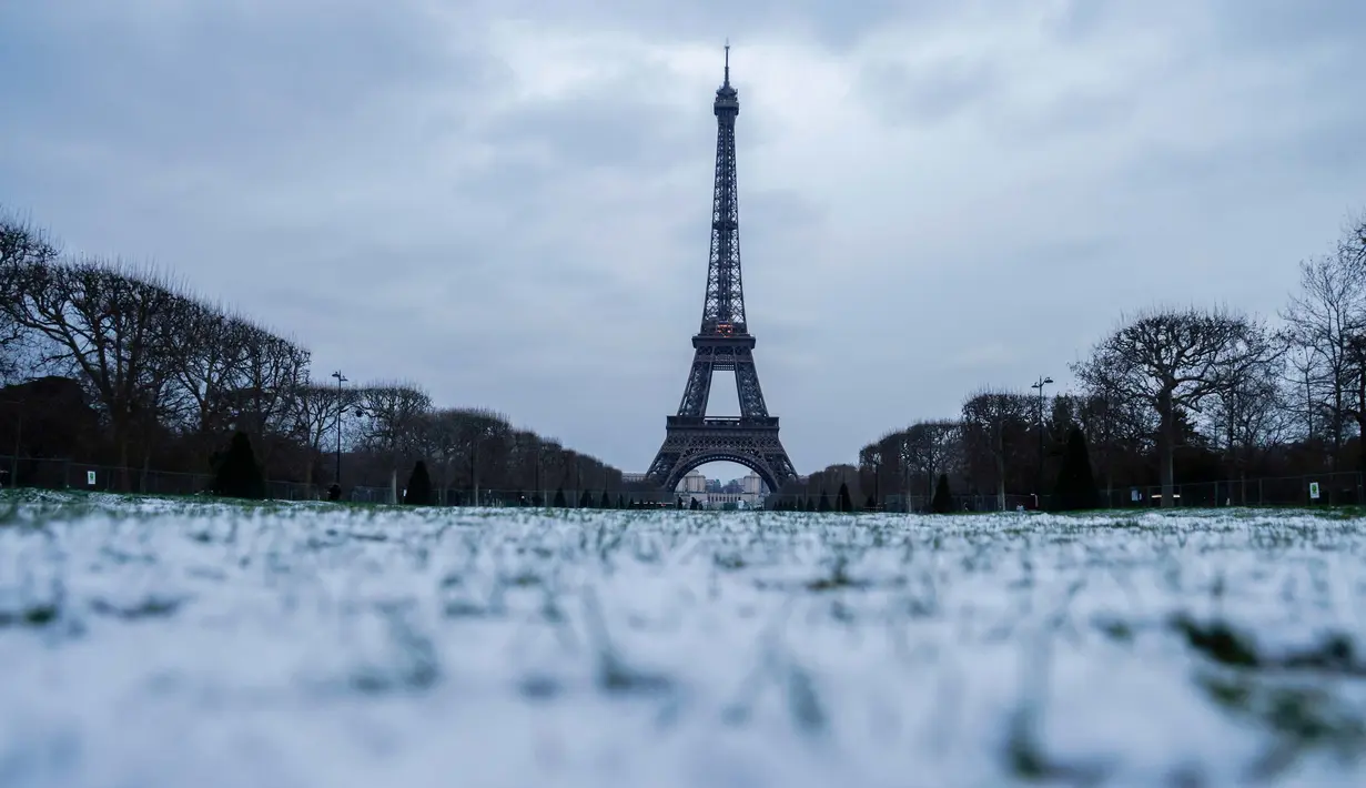 Foto yang diambil di Champ de Mars di Paris pada tanggal 9 Januari 2024, menunjukkan ruang terbuka hijau publik yang luas yang tertutup salju dan Menara Eiffel. (Ludovic MARIN/AFP)