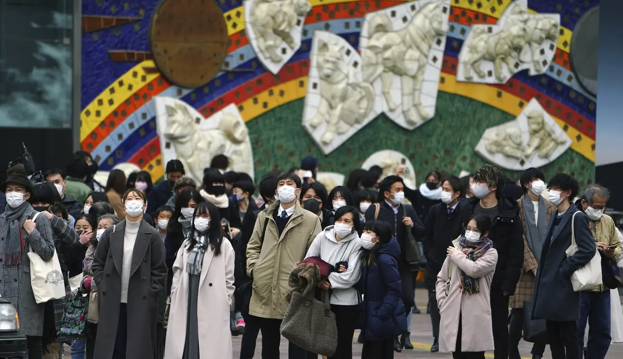 Orang-orang yang mengenakan masker menunggu lampu lalu lintas di penyeberangan pejalan kaki di Shibuya, Tokyo, Selasa (5/1/2021). Pemerintah Jepang sedang mempertimbangkan mendeklarasikan keadaan darurat untuk Tokyo karena kasus infeksi virus corona yang terus meningkat. (AP Photo/Eugene Hoshiko)
