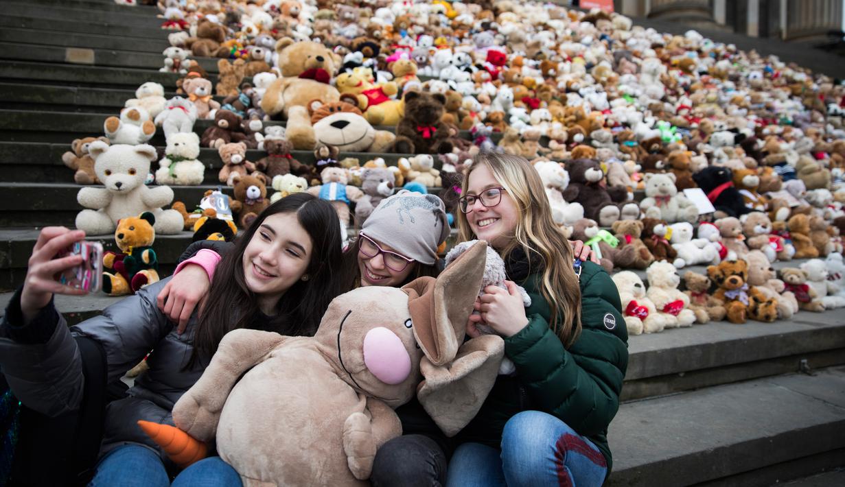 Siswa berswafoto sebelum meletakkan boneka beruang atau Teddy Bears di tangga Concert Hall, Berlin, Kamis (15/3). 740 boneka itu dipajang di tengah kegiatan Organisasi Visi Dunia yang memiliki tujuan misi kemanusiaan. (AFP PHOTO/Odd ANDERSEN)