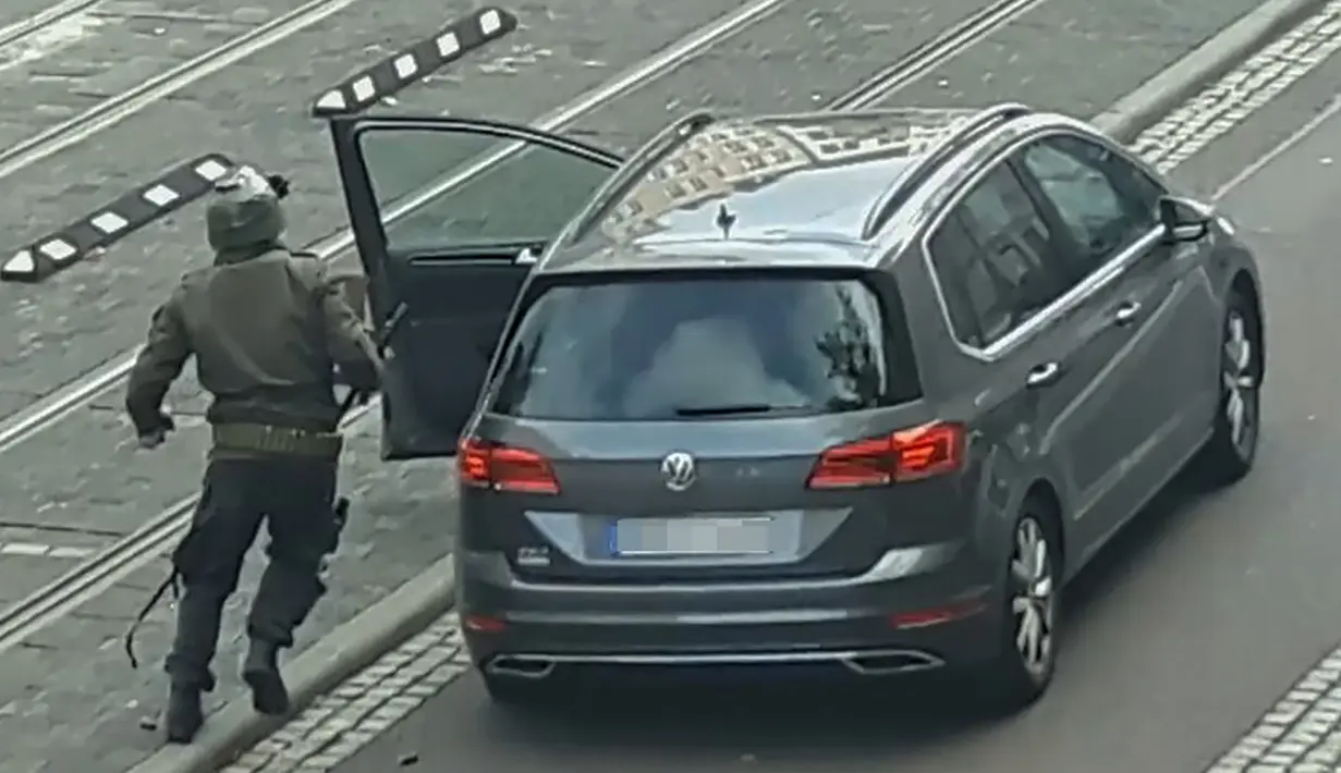 Seorang pria berlari menuju mobil sambil membawa senjata di jalanan Halle an der Saale, Halle, Jerman, Rabu (9/10/2019). Gagal menembus penjagaan sinagoge, pelakuk bergeser dan menyerang toko kebab. (Andreas Splett/ATV-Studio Halle/AFP)