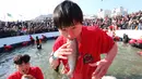 Peserta memegang trout di mulut setelah menangkapnya selama kontes menangkap ikan di Hwacheon, Korea Selatan, Sabtu (5/1). Kontes ini merupakan bagian dari festival es tahunan yang menarik lebih dari satu juta pengunjung setiap tahun. (AP/Ahn Young-joon)