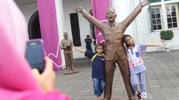 Dua anak berfoto dengan patung Presiden pertama RI Sukarno dipajang di depan Museum Fatahillah, kawasan Kota Tua, Jakarta, Rabu (15/11). Patung karya seniman Dolorosa Sinaga itu dibuat dengan bahan Resin. (Liputan6.com/Immanuel Antonius)