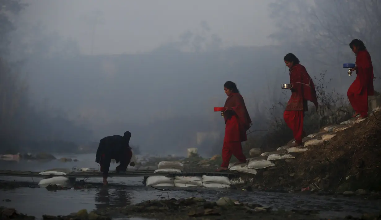 Wanita Hindu Nepal menyebrangi sungai Saali saat festival Swasthani Brata Katha di Kathmandu, Nepal, (24/1). Selama festival umat Hindu Nepal membaca kitab suci Hindu yang didedikasikan untuk dewi Swasthani dan Dewa Siwa. (REUTERS/Navesh Chitrakar)