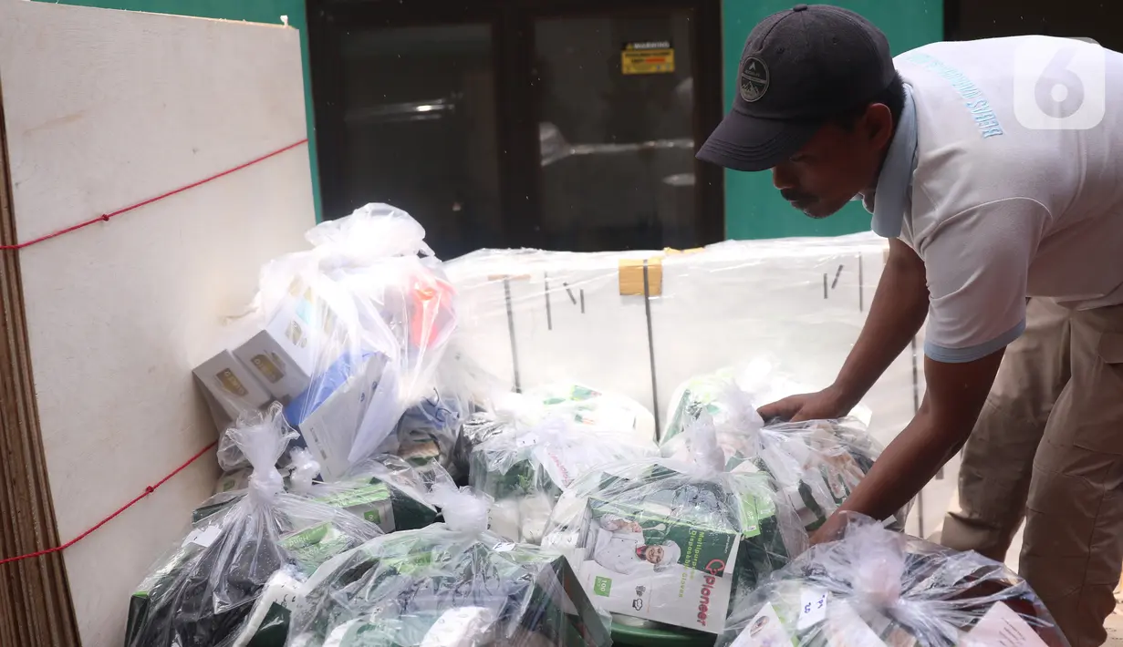 Petugas Panitia Pemungutan Suara (PPS) mendistribusikan alat pelindung diri (APD) untuk setiap TPS di Parigi, Tangerang Selatan, Selasa (8/12/2020). PPS juga menyiapkan APD seperti masker, sarung tangan, baju hazmat, ember pencuci tangan untuk keperluan Pilkada Tangsel. (Liputan6.com/Angga Yuniar)