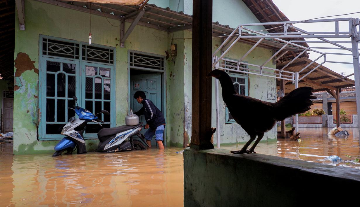 Seorang warga memasuki rumahnya yang terendam banjir di Desa Sukajaya, Serang (1/3/2022).  Berdasarkan data sementara dari Polres Serang Kota, ada 20 titik banjir yang merendam pemukiman warga di Kota Serang. (AFP/Dziki Oktomauliyadi)