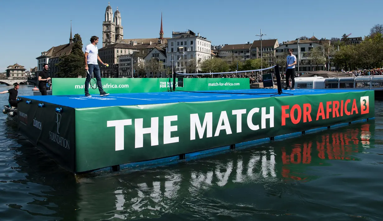 Petenis asal Swiss, Roger Federer (kiri) bertanding melawan petenis asal Inggris, Andy Murray di lapangan kecil di atas sungai Kota Zurich, Senin (10/4). Kedua petenis itu terlibat dalam program amal The Match For Africa 3. (Ennio Leanza/Keystone via AP)