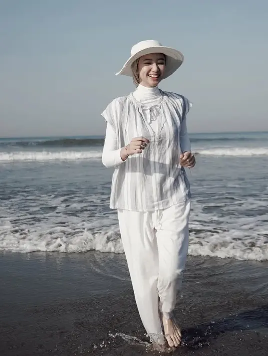 Tampil serba putih saat di pantai, Anselma mengenakan inner halter neck putih dipadukan outer abu-abu bergaris lengan pendek serta celana panjang putih. Ia mengenakan topi pantai putih di atas kerudung turban coklatnya. [@ansellmaputri]