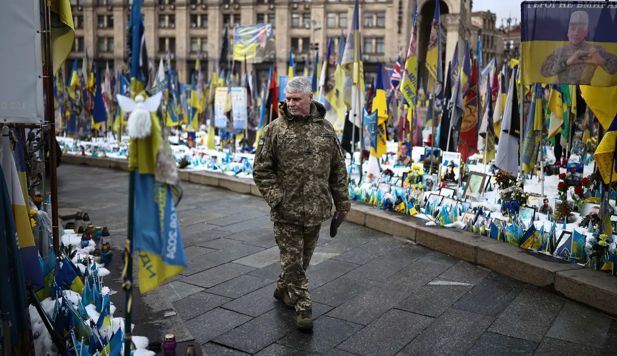 CSIS memperkirakan Rusia beban korban militer sebesar 1,2 juta orang, dengan 325.000 di antaranya tewas. Sementara, Ukraina mengalami kerugian personel hingga 600.000 orang, termasuk 140.000 prajurit yang gugur. Tampak dalam foto, seorang warga setempat mengunjungi tugu peringatan sementara untuk tentara Ukraina dan asing di Lapangan Kemerdekaan, Kyiv, saat peringatan keempat invasi Rusia ke Ukraina, Selasa 24 Februari 2026. (HENRY NICHOLLS/AFP)