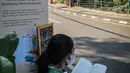 Warga membaca buku dekat perpustakaan bersama Bookhive Jakarta di kawasan Taman Situ Lembang, Jakarta, Selasa (27/4/2021). Rak buku publik tersebut diharapkan bisa memberikan ruang dan menumbuhkan minat baca warga Ibu Kota. (Liputan6.com/Faizal Fanani)