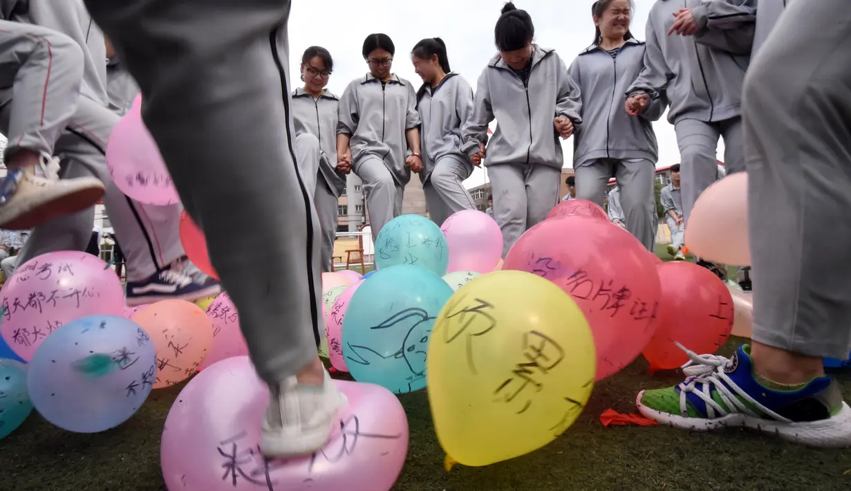 Para siswa menginjak-injak balon melepaskan stres sebelum ujian masuk perguruan tinggi di sebuah sekolah tinggi di Handan, Provinsi Hebei China utara, (24/5). Cara unik ini dilakukan agar para siswanya lebih rileks menghadapi ujian. (AFP PHOTO/STR)
