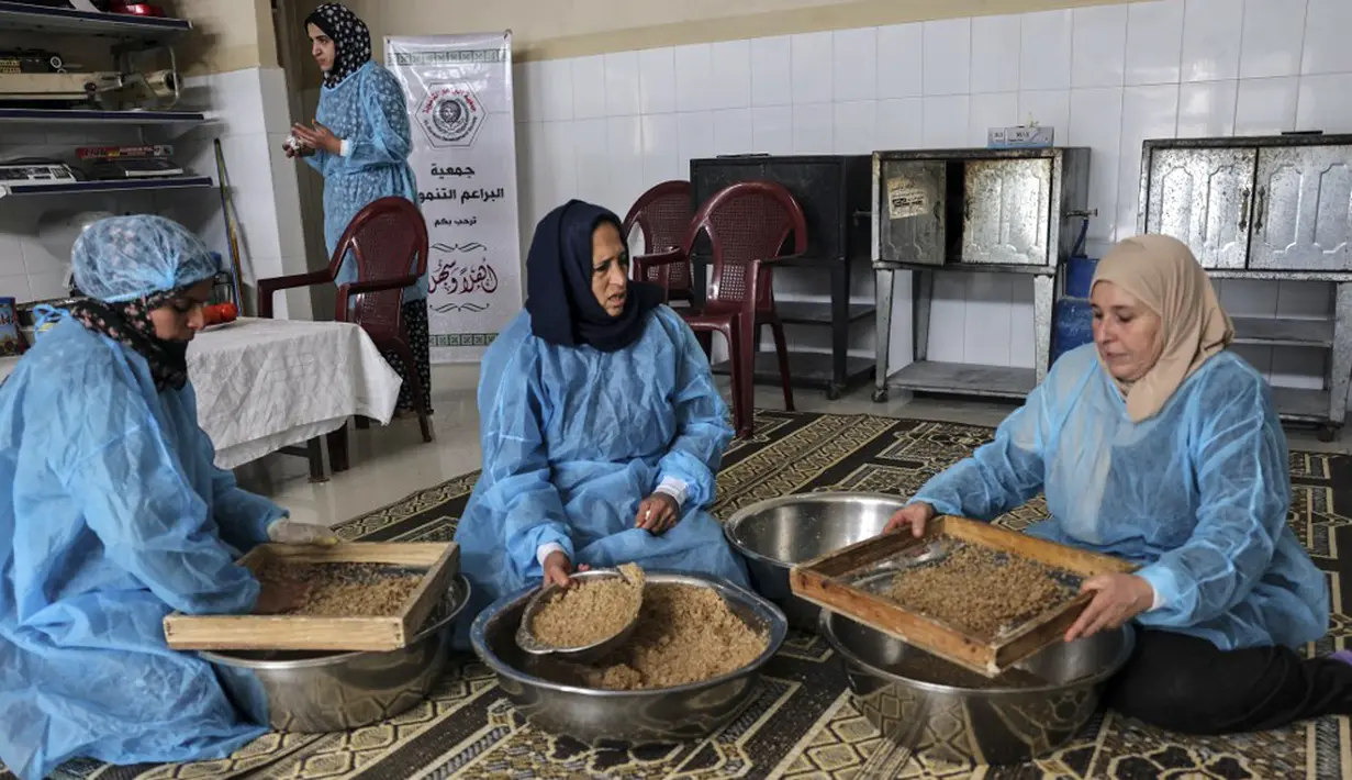 Para wanita membuat maftoul atau couscous di Khan Yunis, Jalur Gaza, Palestina, 10 Januari 2022. Maftoul adalah hidangan tradisional yang terbuat dari gandum bulgur kering. (SAID KHATIB/AFP)