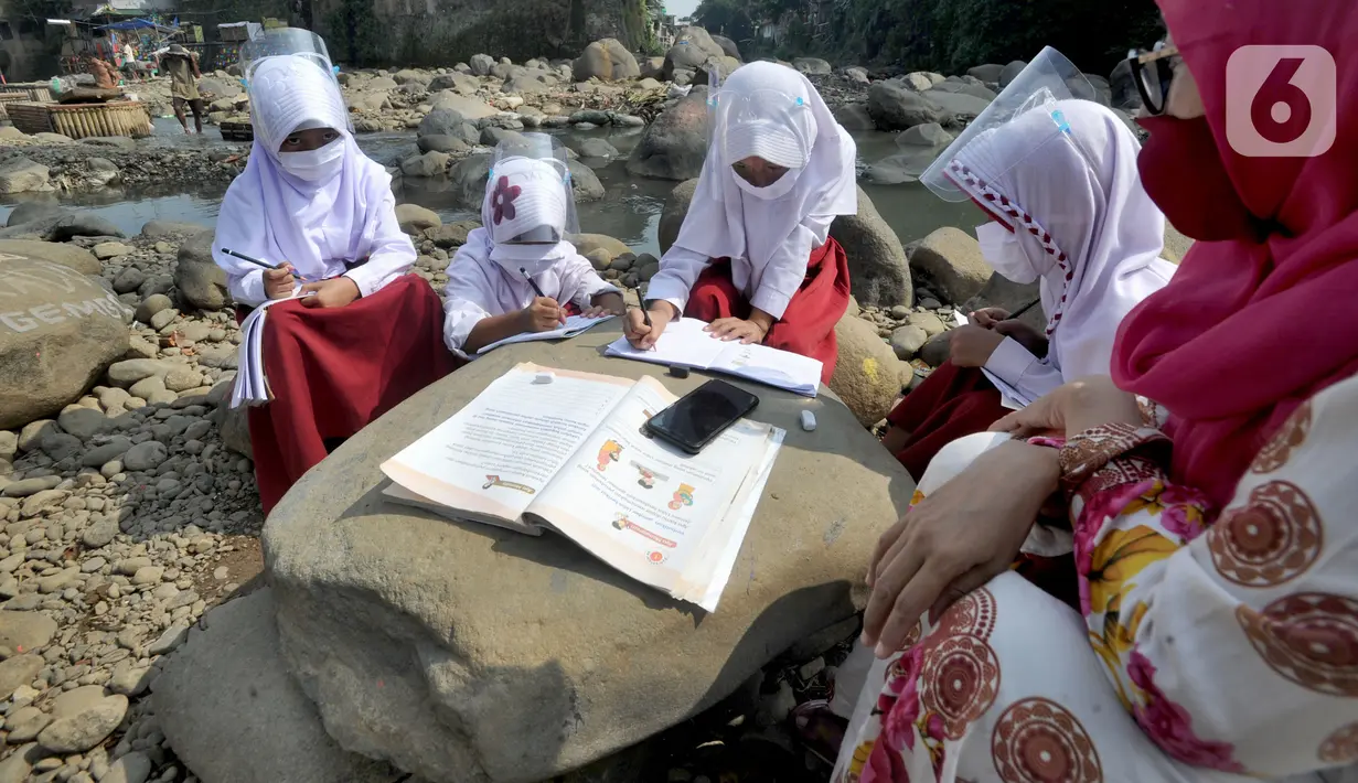 Siswa kelas 3 SDN II Roda Kota Bogor dan pendamping yang memiliki smartphone belajar kelompok secara daring di pinggir sungai Ciliwung, Kampung Kebon Jukut RT 01/10, Babakan Pasar, Kamis (6/8/2020). Kegiatan itu untuk mendapatkan jaringan internet yang baik di masa pandemi. (merdeka.com/Arie Basuki)