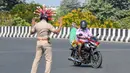 Inspektur polisi Rajesh Babu mengenakan helm berbentuk virus corona saat mengimbau pengendara selama pemberlakukan lockdown di pos pemeriksaan di Chennai, India, Sabtu (28/3/2020). Cara ini agar warga menerapkan social distancing dan tetap berada di rumah selama pandemi Covid-19. (Arun SANKAR/AFP)