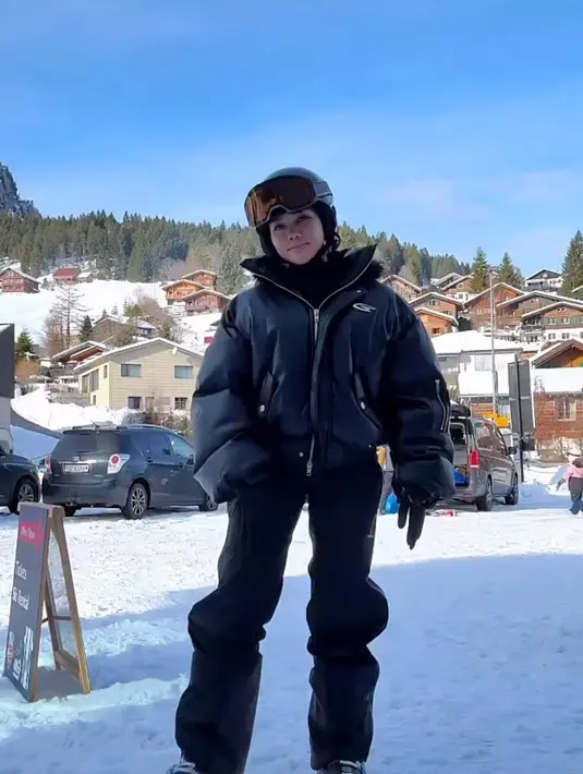 Yura Yunita mencoba bermain ski di Swiss, ia tampil dengan baju ski tebal serba hitam. Dari atasan jaket puffer dipadukan celana panjangnya. [@yurayunita]