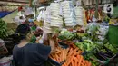 Pedagang sayuran melayani pembeli di kiosnya di Pasar Mede, Jakarta, Rabu (15/12/2021). Harga pangan yang naik antara lain semua jenis cabe, bawang-bawangan serta minyak goreng. (Liputan6.com/Faizal Fanani)