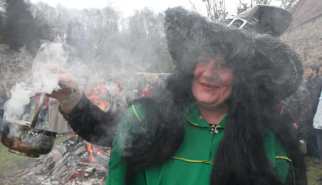 Seorang wanita mengasapi tempat menggelar ritual sihir di acara Walpurgis Night atau Witches Night di Vilnius, Lithuania, Senin (1/5). Orang-orang yang hadir mengenakan atribut layaknya para penyihir. (AFP PHOTO / Petras Malukas)