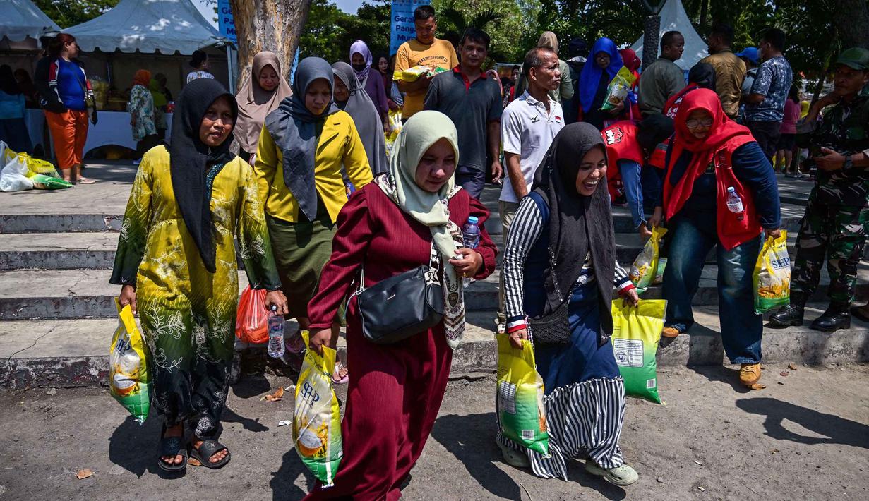 Warga membawa beras usai mengantre membeli kebutuhan pokok di salah satu pasar di Surabaya, Jawa Timur pada Selasa 23 September 2025. (Juni KRISWANTO/AFP)