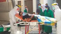 Petugas medis menjemput warga terinfeksi Covid-19 yang menjalani isolasi mandiri di rumah. (Liputan6.com/M Syukur)
