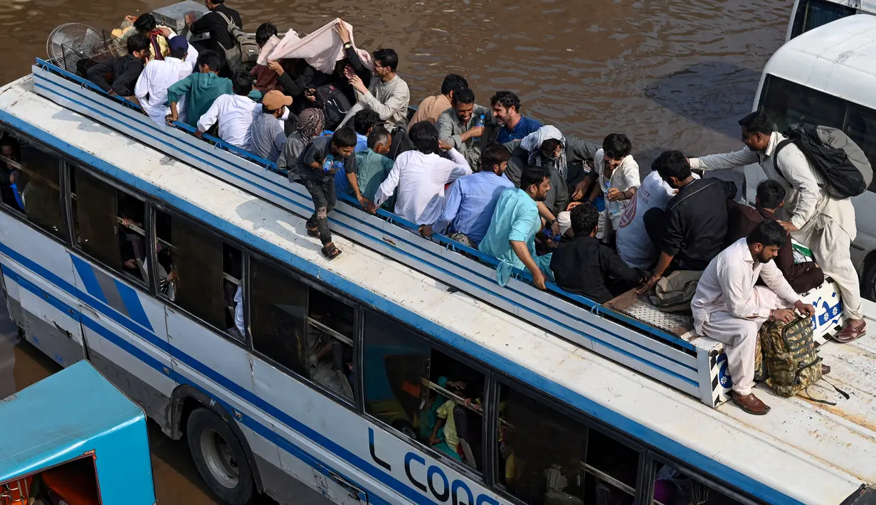 Orang-orang bepergian dengan bus yang penuh sesak menuju kampung halaman mereka menjelang hari raya Idul Adha, di Lahore, Pakistan pada 27 Juni 2023. (Photo by Arif ALI / AFP)