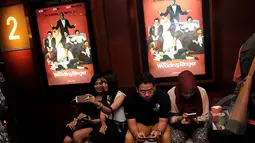 Sambil menunggu studio dibuka, penonton ini selfie sambil duduk dibawah poster film saat Premier Film The Wedding Ringer, Jakarta, Selasa,(17/2/2015) (Liputan6.com/Johan Tallo)