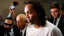 Mantan pemain timnas Brasil, Ronaldinho dikawal oleh polisi meninggalkan kantor pengadilan di Asuncion, ibu kota Paraguay, Jumat (6/3/2020). Ronaldinho bersama saudara laki-lakinya berurusan dengan pihak berwenang Paraguay karena menggunakan paspor palsu untuk memasuki negara itu. (AP/Jorge Saenz)
