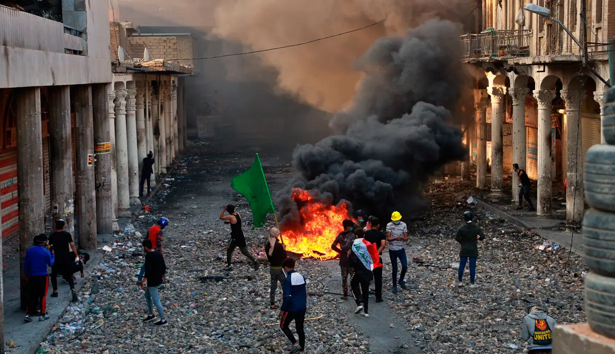 Demonstran antipemerintah membakar barang-barang saat pasukan keamanan menutup Rasheed Street selama bentrok di Baghdad, Irak, Kamis (28/11/2019). Sebanyak 27 demonstran antipemerintah tewas ditembak mati oleh pasukan keamanan Irak dalam sehari. (AP Photo/Khalid Mohammed)