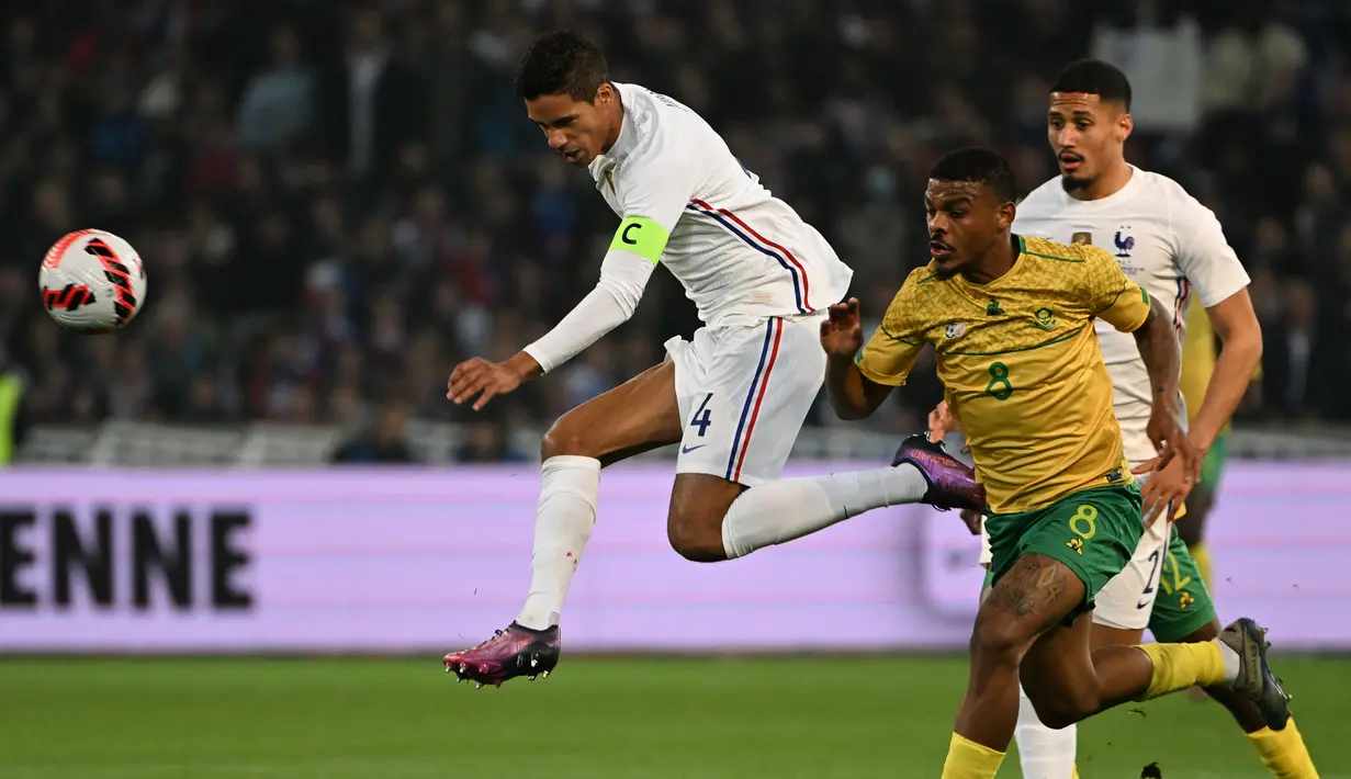Bek Prancis Raphael Varane (tengah) berebut bola dengan penyerang Afrika Selatan Lyle Foster (kanan) dalam laga persahabatan di Stadion Pierre Mauroy, Rabu (30/3/2022) dinihari WIB. Timnas Prancis berpesta lima gol ke gawang Afrika Selatan. (DENIS CHARLET / AFP)