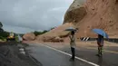 Orang-orang melihat batu-batu besar di jalan raya menuju bandara Narathiwat menyusul tanah longsor setelah hujan lebat di Thailand selatan (25/11/2019). Wilayah selatan Thailand akan memasuki musim hujan lebat tiga bulan dari November hingga Januari. (AFP/Madaree Tohlala)