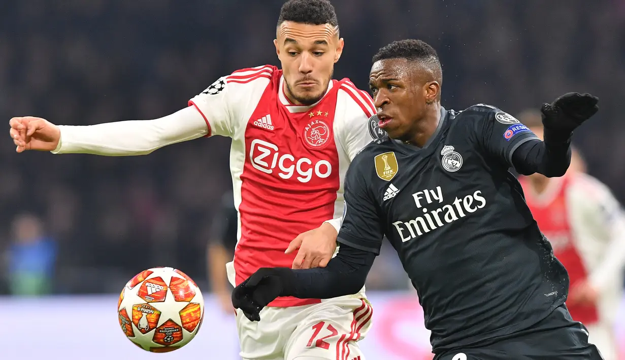 Duel antara Vinicius Jr dan Mazraoiu pada leg 1, 16 besar Liga Champions yang berlangsung di stadion Amsterdam Arena, Amsterdam, Kamis (14/2). Real Madrid menang 2-1 atas Ajax. (AFP/Emmanuel Dunand)