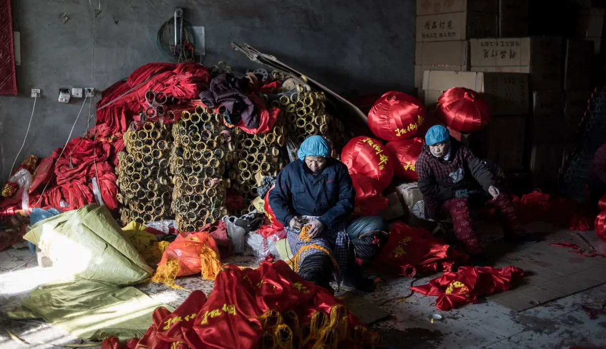 Pekerja membuat rumbai-rumbai untuk lampion merah yang akan dijual menyambut perayaan Tahun Baru Imlek di provinsi Hebei, Tingkok (11/1). (AFP Photo/Fred Dufour)