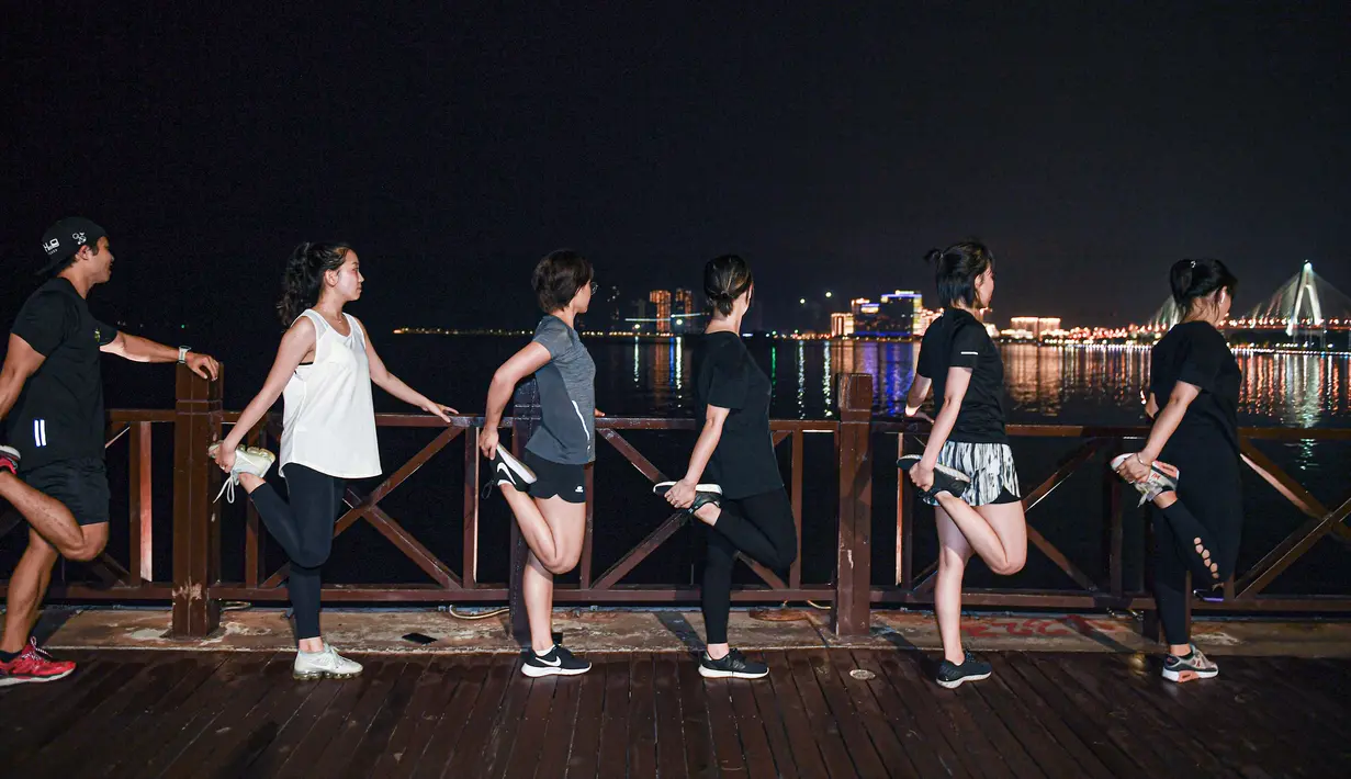 Anggota klub lari merenggangkan tubuh usai berlari di malam hari di Taman Wanlu di Haikou, Provinsi Hainan, China selatan, pada 28 Mei 2020. Berlari di malam hari menjadi olahraga yang populer di kalangan warga Haikou. (Xinhua/Pu Xiaoxu)