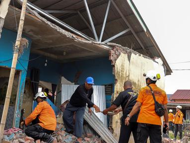 Tim penyelamat membantu warga mencari barang-barang berharga dari reruntuhan rumah mereka yang rusak akibat gempa bumi berkekuatan magnitudo 6,3 di Kelurahan Betungan, Provinsi Bengkulu pada Jumat 23 Mei 2025. (DIVA MARHA/AFP)