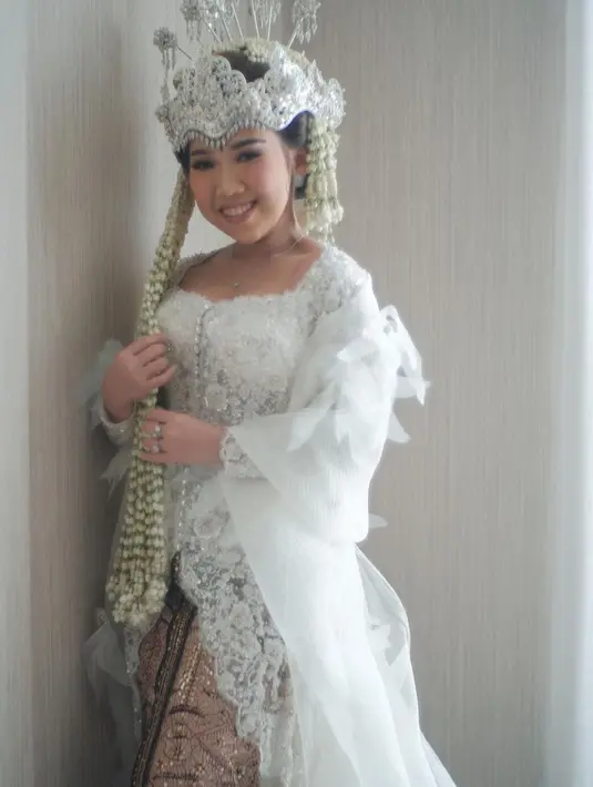 Saat menikah, Kiky Saputri tampil dalam kebaya putih yang dimodifikasi dengan organza. @svarna_byikatindonesia.