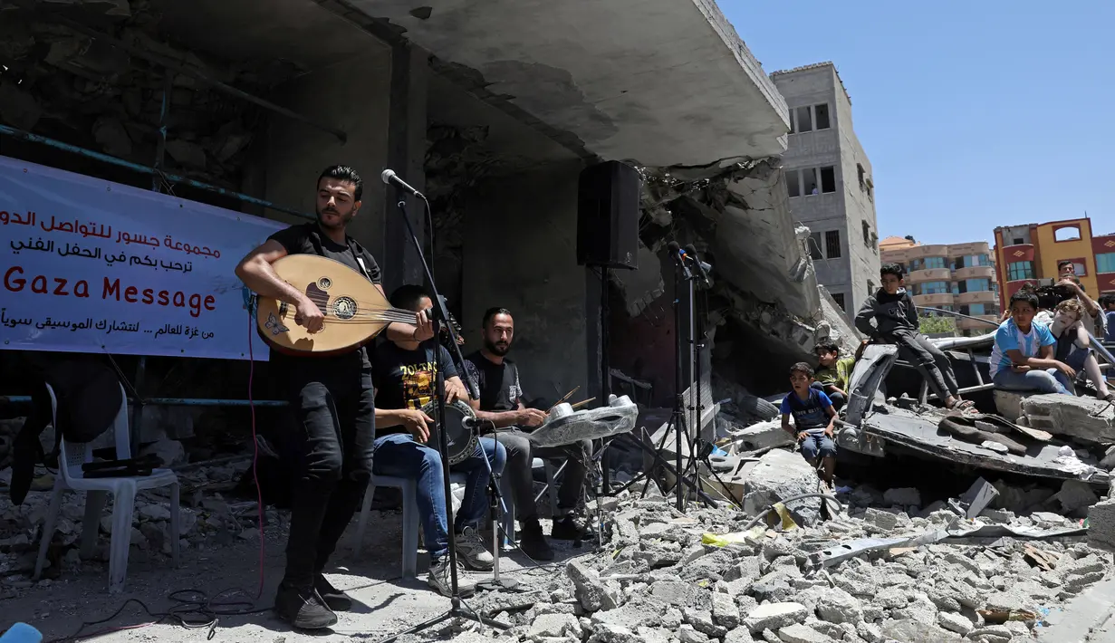 Seorang penyanyi Palestina tampil selama acara musik di puing-puing bangunan yang baru-baru ini hancur oleh serangan udara Israel di kota Gaza, Selasa (14/5/2019). Aksi tersebut untuk menyerukan pemboikotan terhadap Kontes Lagu Eurovision 2019 yang diselenggarakan di Israel. (REUTERS/Mohammed Salem)