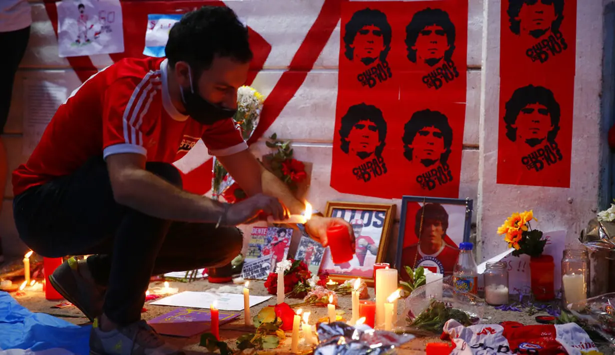 Seorang fans menyalakan lilin untuk Diego Maradona di Buenos Aires, Argentina, Rabu (25/11/2020). legenda sepak bola Argentina itu meninggal dunia pada usia 60 tahun setelah menderita serangan jantung. (AP/Marcos Brindicci)