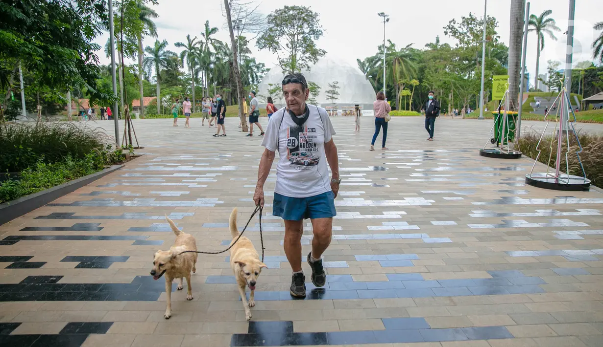 Wisatawan membawa dua ekor anjing saat mengunjungi Senayan Park, Jakarta, Rabu (9/12/2020). Libur Nasional Pilkada Serentak 2020 dimanfaatkan sebagian warga Jakarta dan sekitarnya untuk mengunjungi tempat rekreasi bersama keluarga. (Liputan6.com/Faizal Fanani)