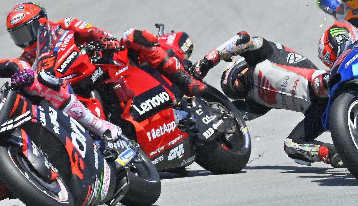 Insiden horor mewarnai jalannya balap MotoGP Catalunya 2022 pada Minggu (05/06/2022) malam WIB. Pebalap LCR Honda, Takaaki Nakagami terjatuh usai ban motor depannya selip ketika mengerem di tikungan pertama. Bahkan, kepalanya sempat membentur roda belakang pebalap Ducati Lenovo, Francesco Bagnaia. (AFP/Pau Barrena)