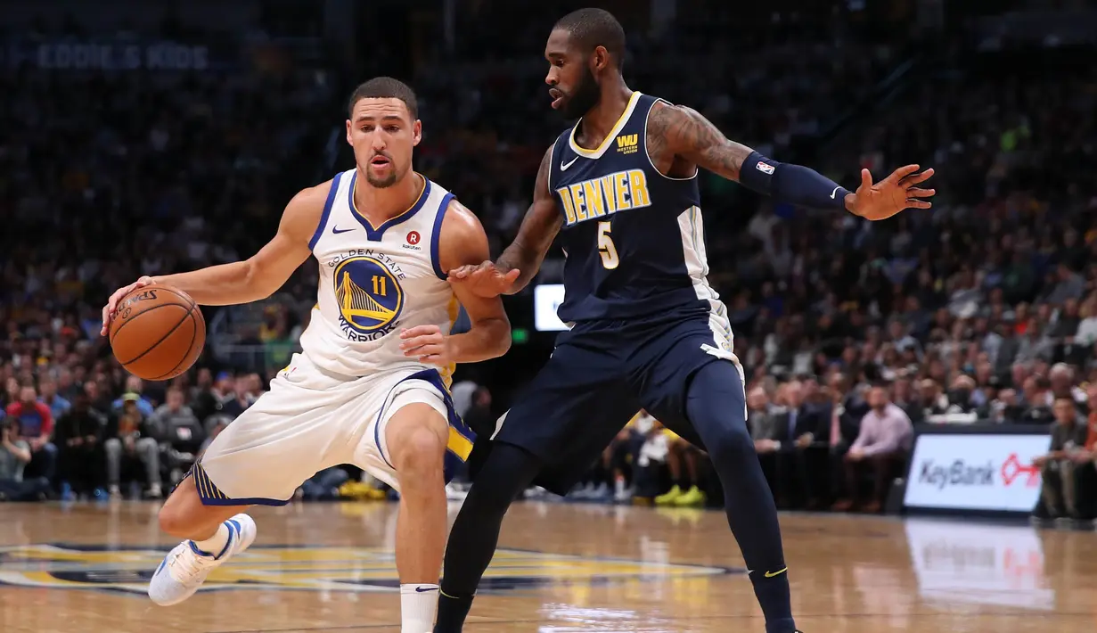 Pebasket Golden State Warriors, Klay Thompson, berusaha melewati pebasket Denver Nuggets, Will Barton, pada laga NBA di Pepsi Center, Denver, Sabtu (4/11/2017). Warriors menang 127-108 atas Nuggets. (AFP/Matthew Stockman)