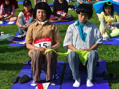 Dua peserta mengikuti ‘Kompetisi Bengong’ atau Space Out Competition di sebuah taman di Seoul, Korea Selatan, (22/5). Sebanyak 60 orang menghabiskan 90 menit duduk tanpa bicara, tidur, makan, apa lagi menggunakan perangkat teknologi. (Jung YEON - JE/AFP)