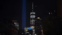 'Tribute in Light'  dinyalakan untuk memperingati serangan gedung kembar WTC yang terlihat di dekat gedung One World Trade Center, New York City, Selasa (10/9/2019). Cahaya kembar itu jadi simbol menara kembar WTC yang hancur diserang kelompok pembajak pesawat 18 tahun silam. (Johannes EISELE/AFP)